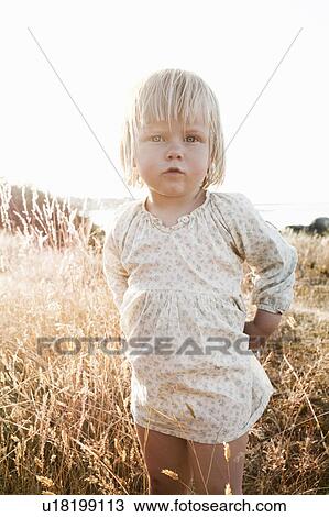 Stock Image - Toddler girl standing in wheatfield. Fotosearch