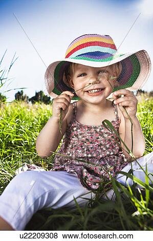 Toddler girl wearing sunhat in grass View Large Photo Image Stock Photo - Toddler girl wearing sunhat in grass. Fotosearch