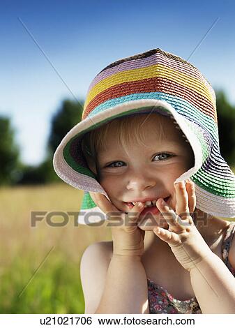 Stock Photograph - Toddler girl wearing sunhat outdoors. Fotosearch