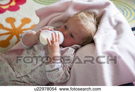 Picture - Toddler in blanket drinking from bottle. Fotosearch