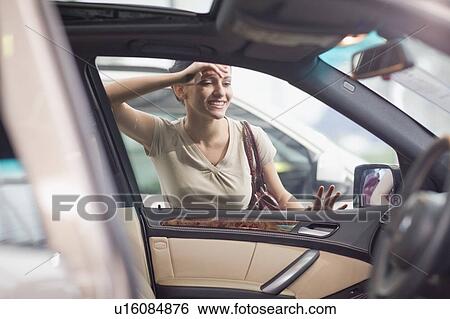 Stock Photograph - Woman admiring car in showroom. Fotosearch