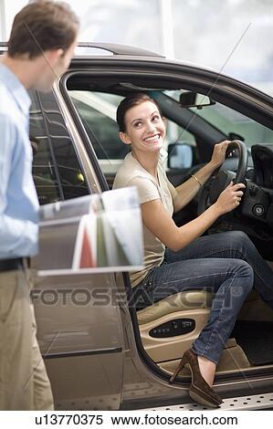 Stock Photography - Woman admiring car in showroom. Fotosearch