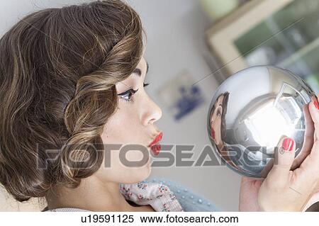 Stock Photography - Woman admiring herself in mirrored ball. Fotosearch
