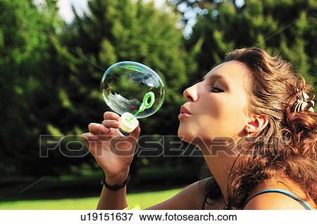 Stock Photo - Woman blowing bubbles in park. Fotosearch
