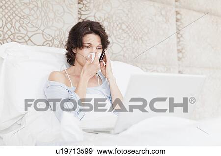 Woman blowing her nose in bed View Large Photo Image Stock Photo - Woman blowing her nose in bed. Fotosearch