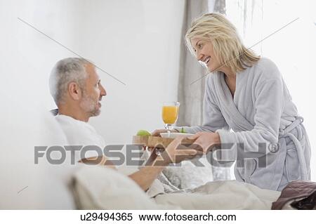 Stock Photography - Woman bringing husband breakfast in bed. Fotosearch