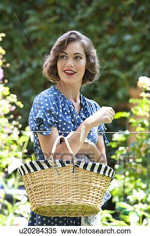 Stock Photography - Woman carrying basket in backyard. Fotosearch