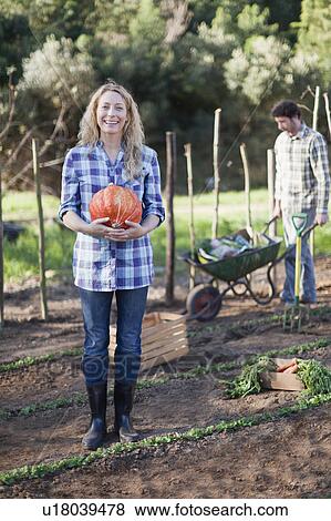 Stock Photo - Woman carrying gourd in garden. Fotosearch