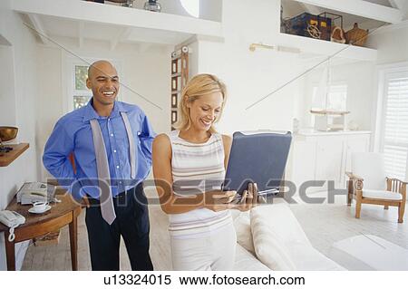 Stock Photography - Woman carrying laptop in living room. Fotosearch
