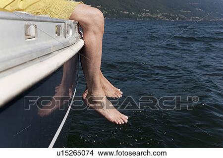 Picture - Woman dangling feet from sailboat. Fotosearch