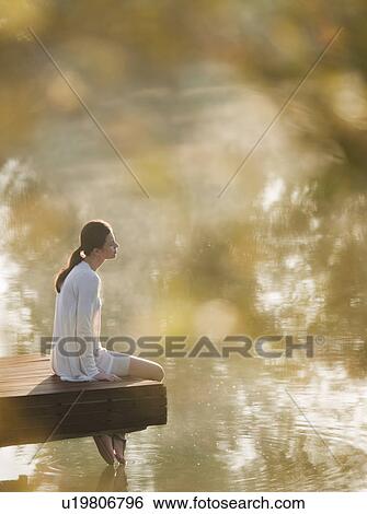 Stock Photograph - Woman dangling her feet in lake. Fotosearch
