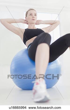 Picture - Woman doing crunches with exercise ball. Fotosearch