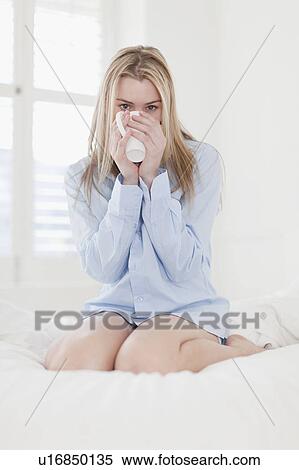 Stock Photography - Woman drinking cup of coffee on bed. Fotosearch
