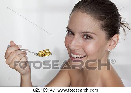 Stock Photo - Woman eating spoonful of supplements. Fotosearch