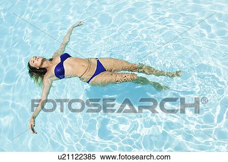 Stock Photography - Woman floating in swimming pool. Fotosearch