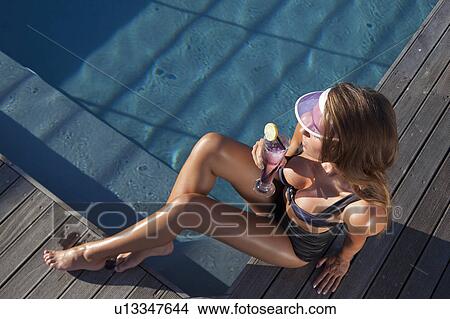 Picture - Woman having a drink by pool. Fotosearch