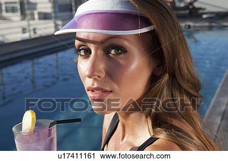 Stock Image - Woman having a drink by pool. Fotosearch