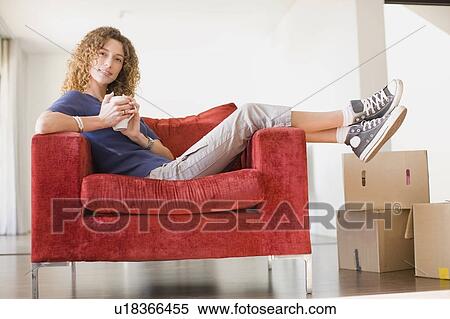 Stock Photography - Woman having coffee in armchair. Fotosearch