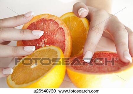 Stock Image - Woman holding halved citrus fruits. Fotosearch