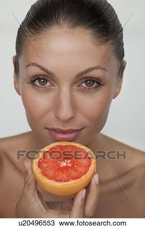 Stock Image - Woman holding halved grapefruit. Fotosearch