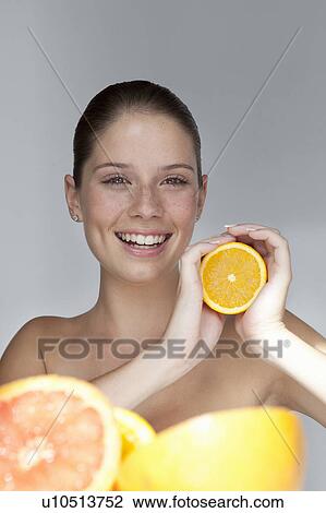 Stock Image - Woman holding halved orange. Fotosearch