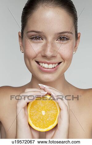 Stock Photo - Woman holding halved orange. Fotosearch