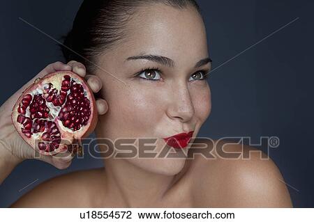 Stock Image - Woman holding halved pomegranate. Fotosearch