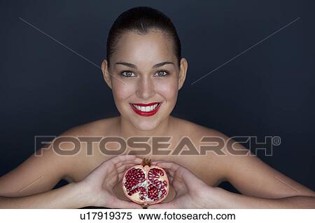 Stock Photography - Woman holding halved pomegranate. Fotosearch