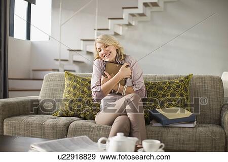Stock Photo - Woman hugging framed photo on couch. Fotosearch
