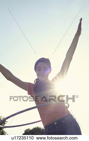 Stock Image - Woman hula hooping outdoors. Fotosearch