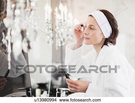 Woman in bathrobe applying makeup View Large Photo Image Picture - Woman in bathrobe applying makeup. Fotosearch