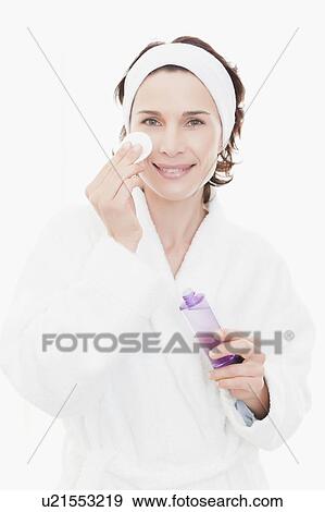 Stock Photo - Woman in bathrobe cleansing her face. Fotosearch
