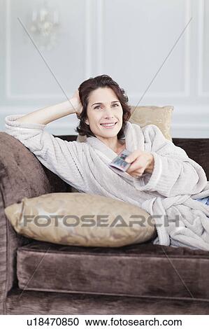 Stock Image - Woman in bathrobe watching television. Fotosearch