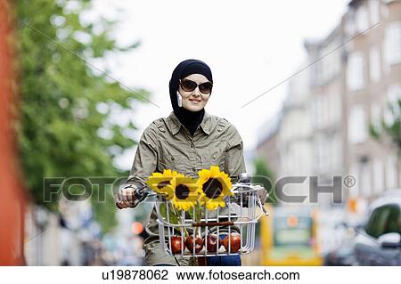 Woman in headscarf biking on cell phone View Large Photo Image Stock Image - Woman in headscarf biking on cell phone. Fotosearch