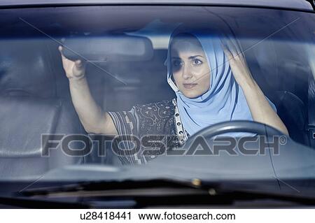 Stock Image - Woman in headscarf checking mirror. Fotosearch