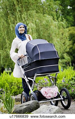 Woman in headscarf pushing stroller View Large Photo Image Stock Photo - Woman in headscarf pushing stroller. Fotosearch