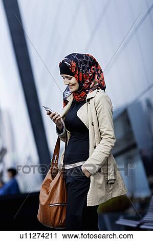 Stock Image - Woman in headscarf using cell phone. Fotosearch