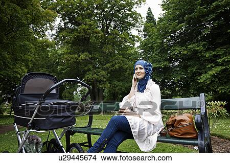 Picture - Woman in headscarf with stroller in park. Fotosearch