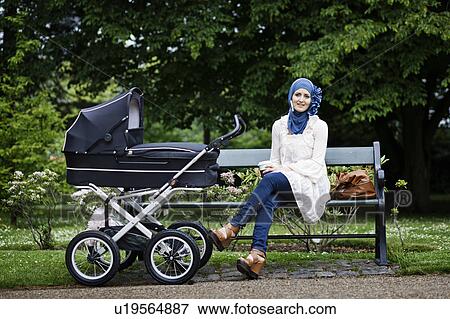 Woman in headscarf with stroller in park View Large Photo Image Stock Photo - Woman in headscarf with stroller in park. Fotosearch