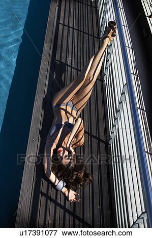 Stock Photo - Woman in swimsuit laying by pool. Fotosearch