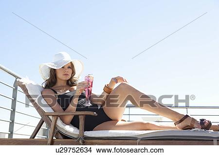 Woman in swimsuit relaxing in lawn chair View Large Photo Image Picture - Woman in swimsuit relaxing in lawn chair. Fotosearch