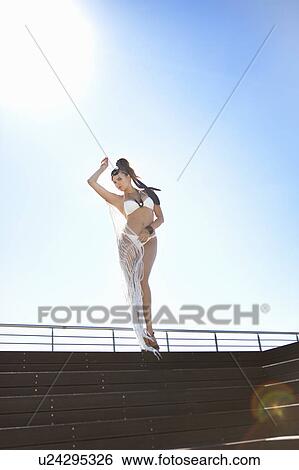 Stock Photograph - Woman in swimsuit standing on steps. Fotosearch