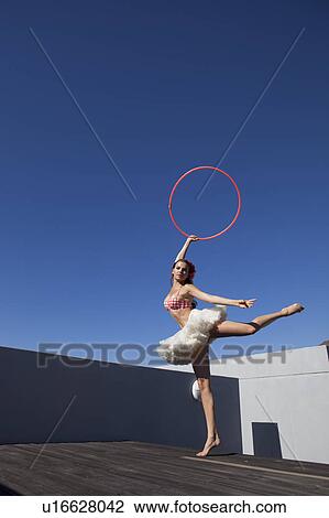 Stock Image - Woman in tutu dancing with hula hoop. Fotosearch