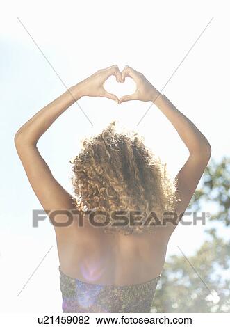 Stock Image - Woman making heart shape with hands. Fotosearch