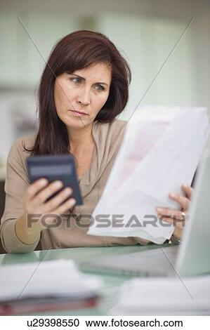 Stock Image - Woman paying her bills at home. Fotosearch