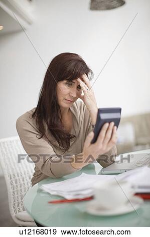 Stock Photo - Woman paying her bills at home. Fotosearch