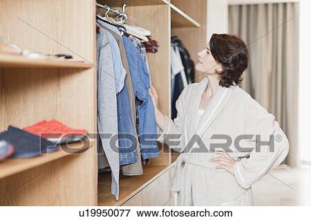 Stock Photo - Woman picking clothes out of closet. Fotosearch