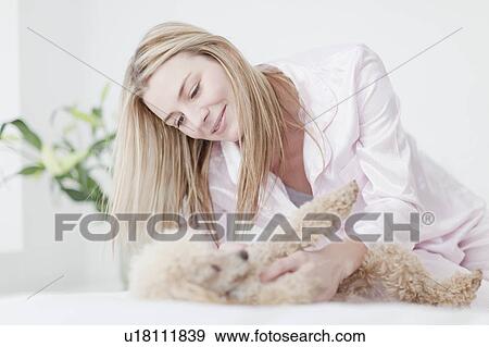 Stock Photo - Woman playing with dog on bed. Fotosearch