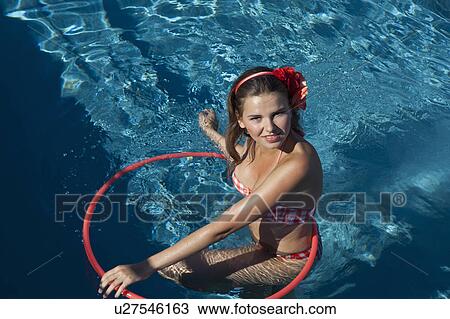Stock Image - Woman playing with hula hoop in pool. Fotosearch