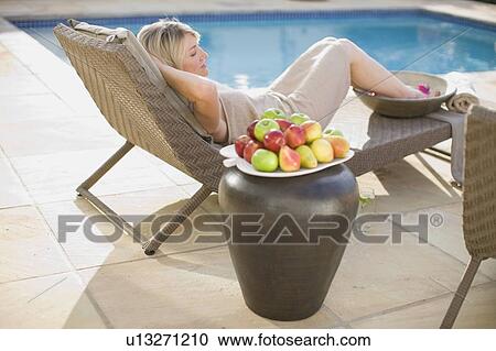 Woman relaxing in lawn chair by pool View Large Photo Image Stock Image - Woman relaxing in lawn chair by pool. Fotosearch
